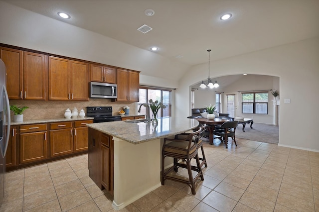 760 Red Elm Ln, Fort Worth, TX 76131 - kitchen featuring black range with electric cooktop, stainless steel microwave, brown cabinetry, a sink, and vaulted ceiling