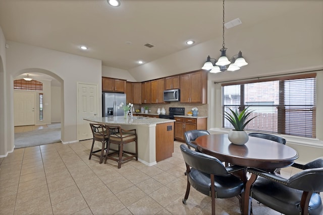 760 Red Elm Ln, Fort Worth, TX 76131 - kitchen featuring appliances with stainless steel finishes, arched walkways, lofted ceiling, a chandelier, and brown cabinetry