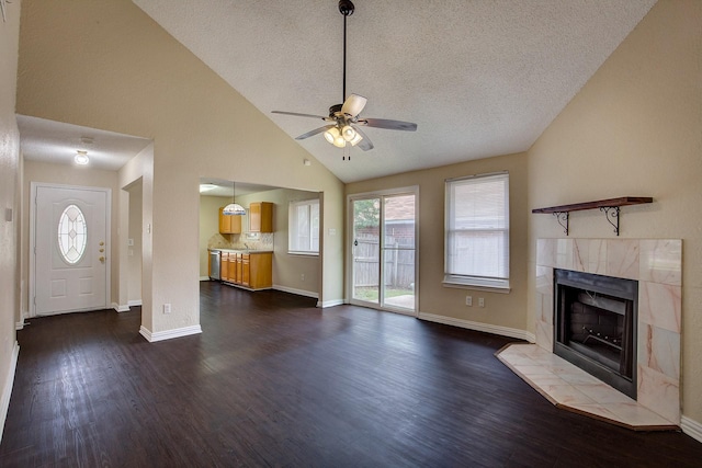 6729 Windwillow Dr, Fort Worth, TX 76137 - unfurnished living room featuring a ceiling fan, dark wood-type flooring, a tile fireplace, a textured ceiling, and baseboards