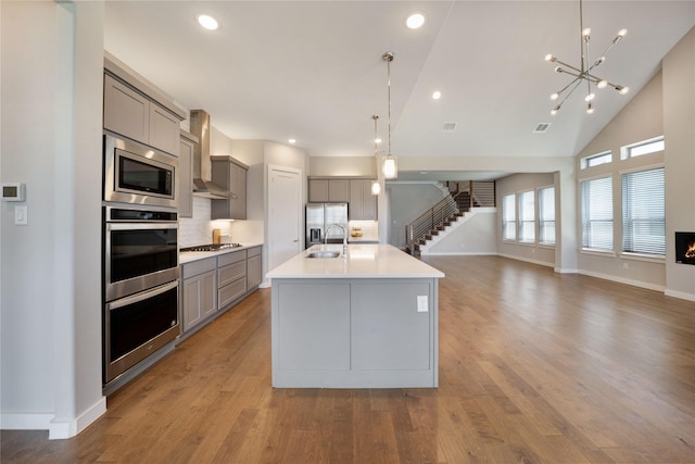 3493 Hollow Pine Dr, Frisco, TX 75033 - kitchen featuring gray cabinets, wall chimney range hood, a sink, appliances with stainless steel finishes, and open floor plan