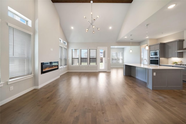3493 Hollow Pine Dr, Frisco, TX 75033 - kitchen featuring gray cabinetry, appliances with stainless steel finishes, light countertops, high vaulted ceiling, and a center island with sink