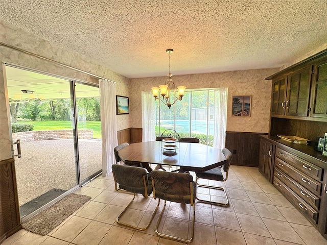 1107 Rock Springs Rd, Duncanville, TX 75137 - dining room featuring wainscoting, a chandelier, a textured ceiling, light tile patterned flooring, and wooden walls