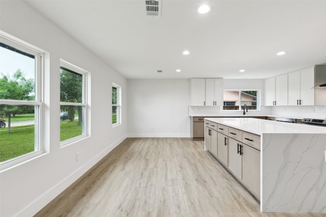 1309 Northpark Dr, Richardson, TX 75081 - kitchen featuring light wood-style flooring, recessed lighting, baseboards, white cabinets, and light stone countertops