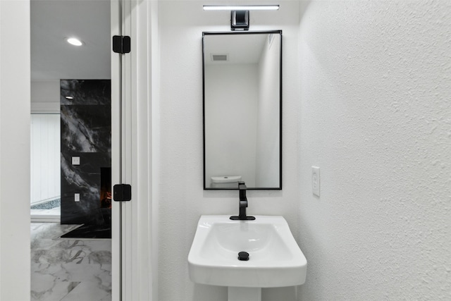 1309 Northpark Dr, Richardson, TX 75081 - bathroom with marble look tile flooring, a sink, and a textured wall