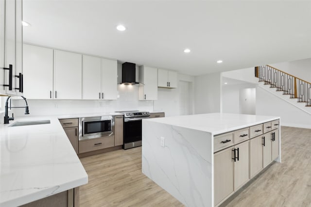 1309 Northpark Dr, Richardson, TX 75081 - kitchen featuring stainless steel appliances, a sink, wall chimney range hood, a kitchen island, and light wood finished floors
