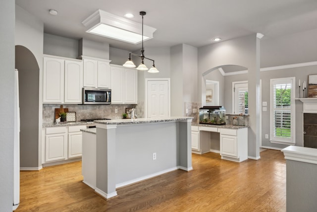 7308 Claridge Ln, Mckinney, TX 75072 - kitchen featuring stainless steel microwave, arched walkways, white cabinetry, decorative backsplash, and recessed lighting