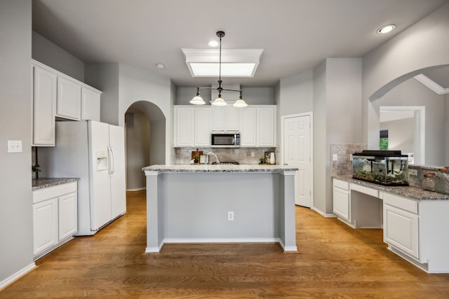 7308 Claridge Ln, Mckinney, TX 75072 - kitchen with arched walkways, white refrigerator with ice dispenser, stainless steel microwave, decorative backsplash, and recessed lighting