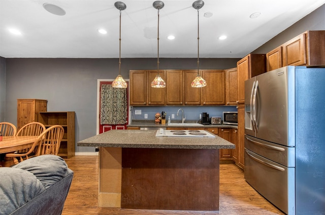 6811 Pecan St, Frisco, TX 75034 - kitchen featuring stainless steel appliances, a sink, dark countertops, a kitchen island, and light wood-style flooring