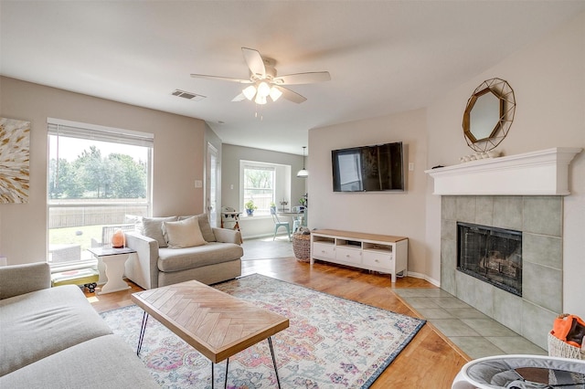 412 Hanover St, Burleson, TX 76028 - living room featuring ceiling fan, a tiled fireplace, and light wood-type flooring