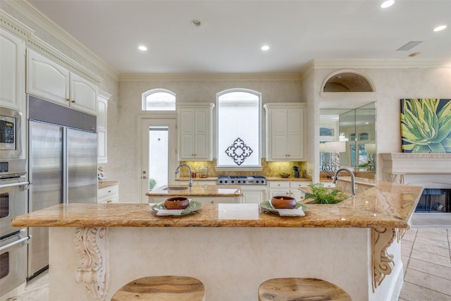 5528 Gleneagles Dr, Plano, TX 75093 - kitchen featuring a large island, a kitchen breakfast bar, light stone counters, a sink, and crown molding