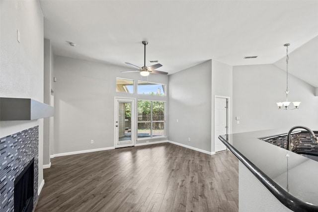 5409 Highlands Dr, Mckinney, TX 75070 - unfurnished living room featuring ceiling fan, wood finished floors, baseboards, a tiled fireplace, and a chandelier
