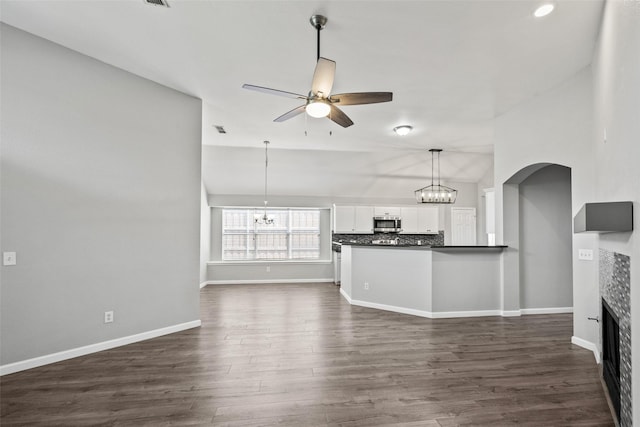 5409 Highlands Dr, Mckinney, TX 75070 - unfurnished living room featuring ceiling fan, a chandelier, a fireplace, vaulted ceiling, and dark wood-style flooring