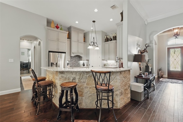 1447 Cimarron Trl, Hurst, TX 76053 - kitchen with stainless steel refrigerator with ice dispenser, arched walkways, dark wood-style flooring, a breakfast bar, and ornamental molding