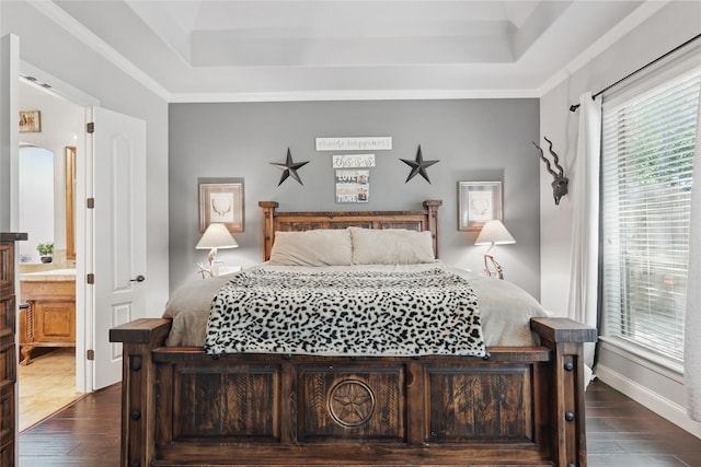 1447 Cimarron Trl, Hurst, TX 76053 - bedroom featuring a raised ceiling, wood finished floors, baseboards, and connected bathroom