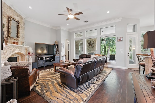 1447 Cimarron Trl, Hurst, TX 76053 - living area featuring a stone fireplace, a ceiling fan, dark wood finished floors, ornamental molding, and arched walkways