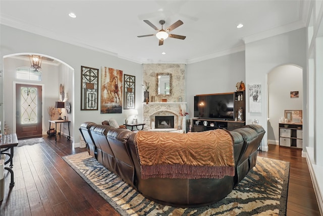 1447 Cimarron Trl, Hurst, TX 76053 - living area with arched walkways, ceiling fan, dark wood-type flooring, a stone fireplace, and ornamental molding