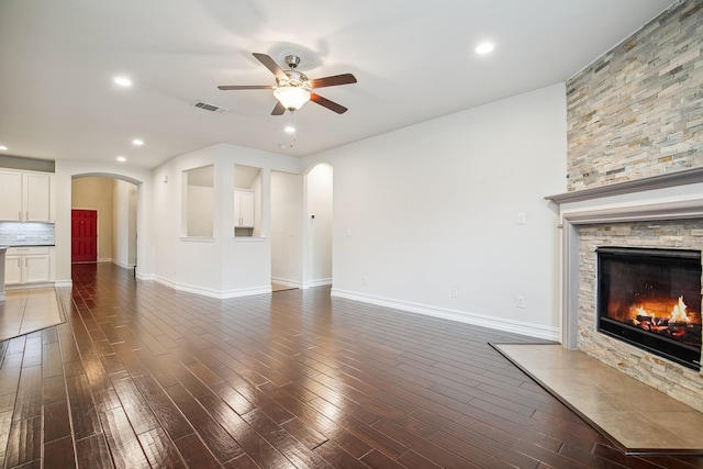 2341 Leeward Pl, Little Elm, TX 75068 - unfurnished living room with arched walkways, a ceiling fan, a fireplace, recessed lighting, and dark wood-type flooring