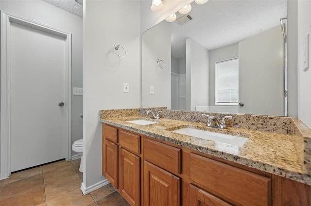 1412 Mockingbird Ln, Desoto, TX 75115 - bathroom featuring a textured ceiling, double vanity, toilet, and tile patterned floors