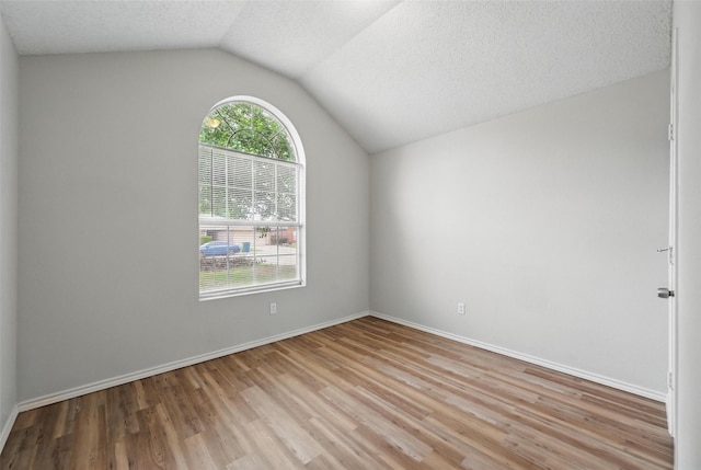 1412 Mockingbird Ln, Desoto, TX 75115 - unfurnished room with healthy amount of natural light, lofted ceiling, light wood-type flooring, baseboards, and a textured ceiling