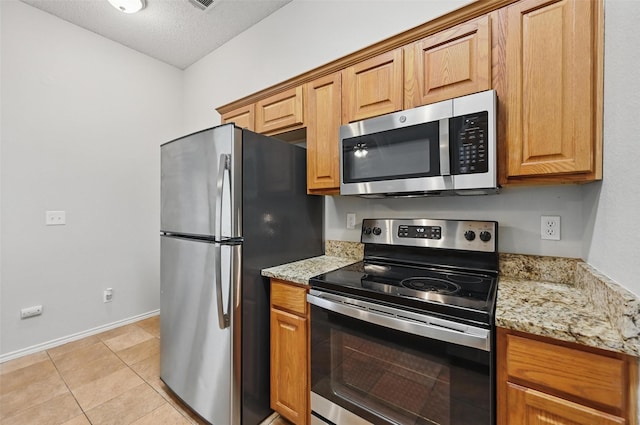 1412 Mockingbird Ln, Desoto, TX 75115 - kitchen featuring stainless steel appliances, baseboards, light stone countertops, light tile patterned floors, and a textured ceiling