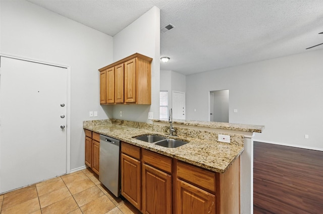 1412 Mockingbird Ln, Desoto, TX 75115 - kitchen with stainless steel dishwasher, a sink, a peninsula, light stone countertops, and a textured ceiling