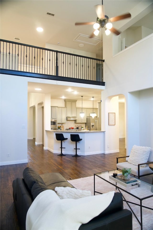 4561 Firewheel Dr, Plano, TX 75024 - living room featuring arched walkways, a towering ceiling, ceiling fan, dark wood finished floors, and baseboards