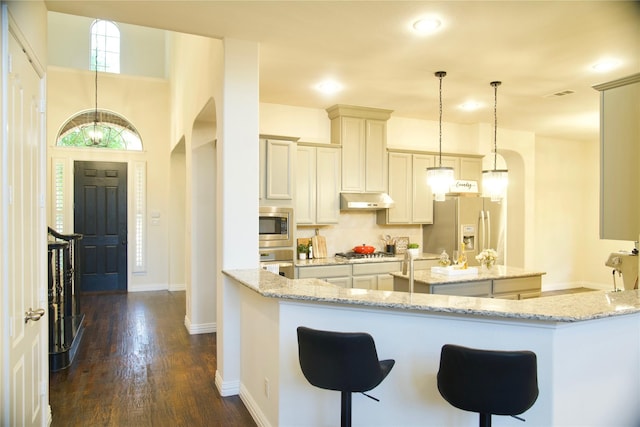 4561 Firewheel Dr, Plano, TX 75024 - kitchen featuring appliances with stainless steel finishes, under cabinet range hood, a kitchen island, dark wood-type flooring, and baseboards