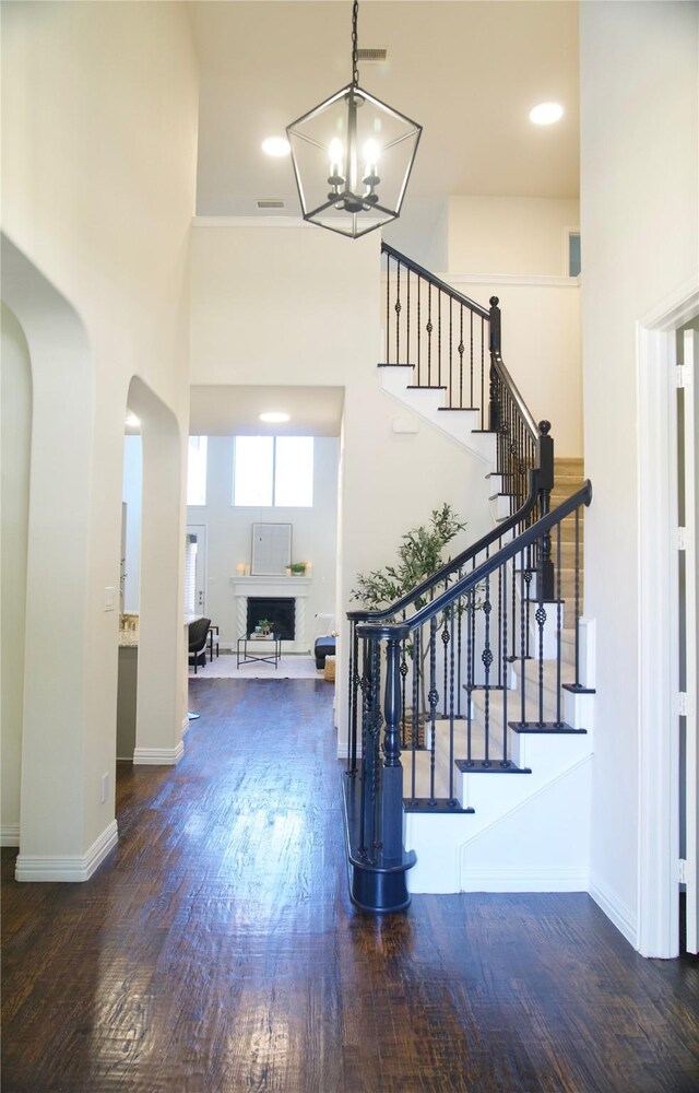 4561 Firewheel Dr, Plano, TX 75024 - entryway with stairs, wood finished floors, a chandelier, a fireplace, and arched walkways