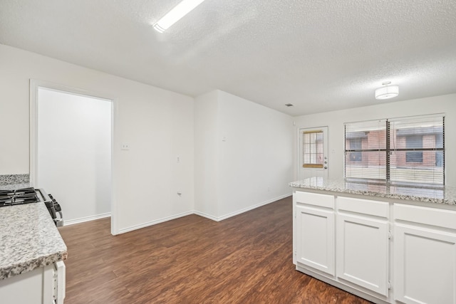 1713 Carrington, Glenn Heights, TX 75154 - kitchen featuring a textured ceiling, dark wood-style floors, white cabinetry, baseboards, and range with gas stovetop