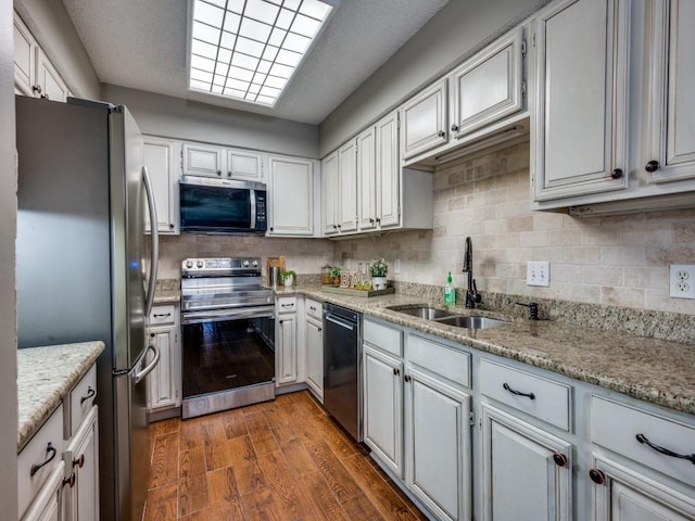 46 Morrow Dr, Bedford, TX 76021 - kitchen featuring stainless steel appliances, a sink, decorative backsplash, light stone counters, and white cabinets