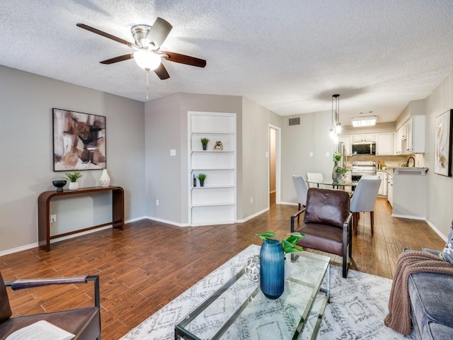 46 Morrow Dr, Bedford, TX 76021 - living room featuring built in features, a textured ceiling, baseboards, and ceiling fan