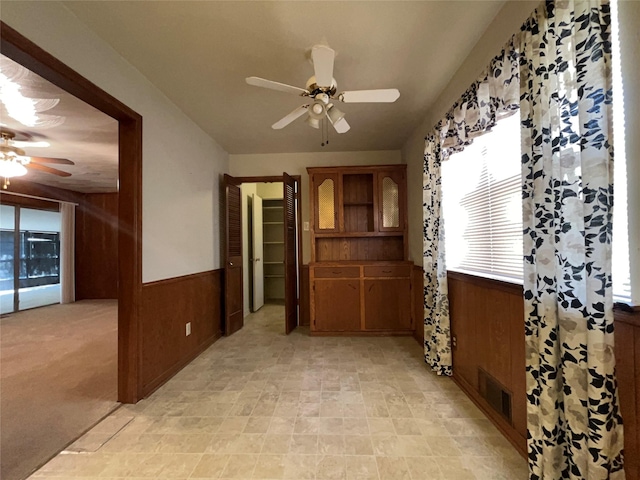 3614 Matador Dr, Garland, TX 75042 - unfurnished dining area with a ceiling fan, wood walls, and a wainscoted wall