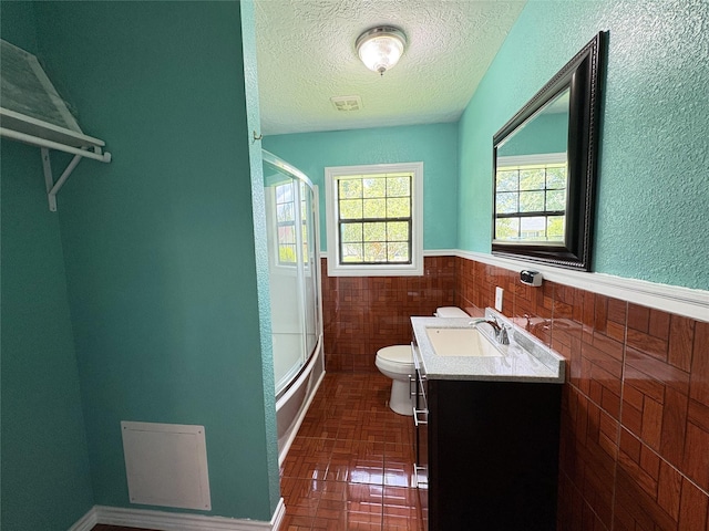 1205 Lamar, Mount Pleasant, TX 75455 - bathroom featuring toilet, brick patterned floors, vanity, a textured ceiling, and wainscoting