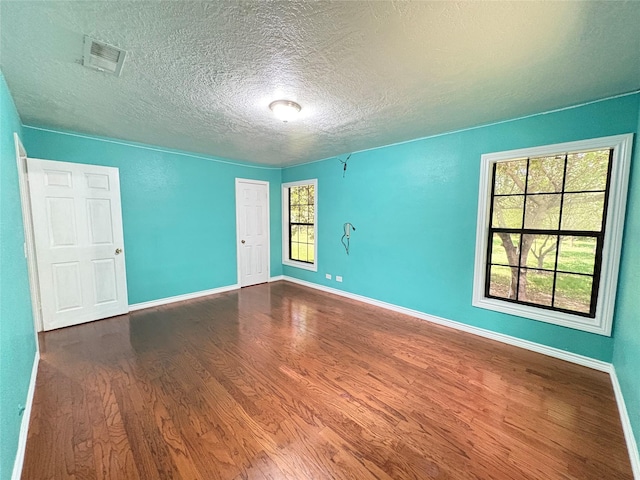 1205 Lamar, Mount Pleasant, TX 75455 - spare room with dark wood finished floors, a textured ceiling, and baseboards