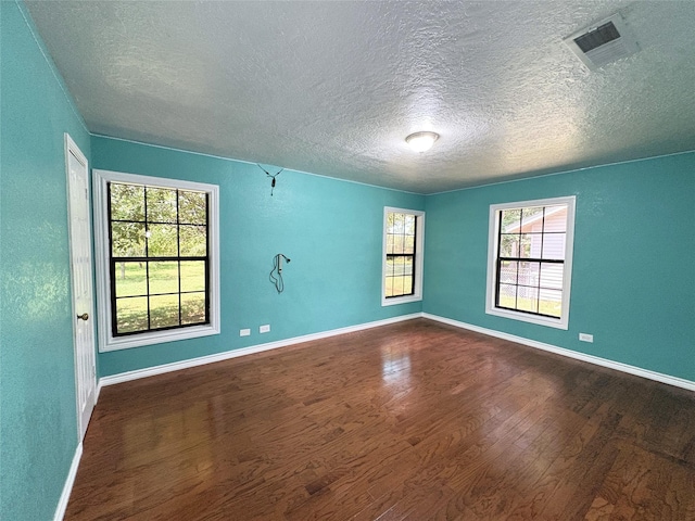 1205 Lamar, Mount Pleasant, TX 75455 - spare room featuring a textured ceiling, dark wood-style flooring, and baseboards