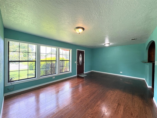 1205 Lamar, Mount Pleasant, TX 75455 - unfurnished living room featuring a textured ceiling, dark wood-style flooring, and baseboards