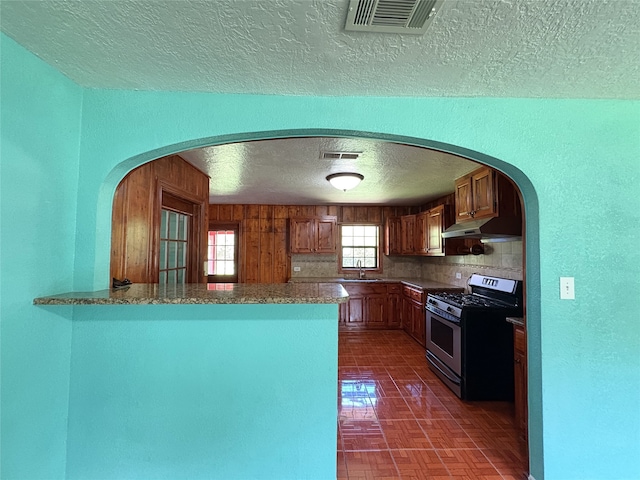 1205 Lamar, Mount Pleasant, TX 75455 - kitchen featuring stainless steel gas range oven, a sink, a textured ceiling, a peninsula, and under cabinet range hood