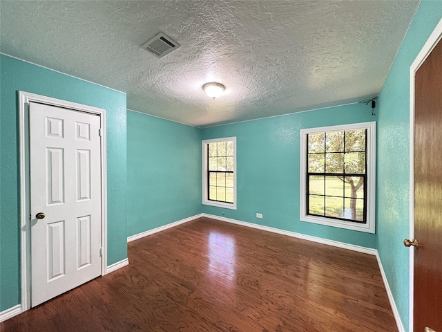 1205 Lamar, Mount Pleasant, TX 75455 - spare room with wood finished floors, healthy amount of natural light, a textured ceiling, and baseboards