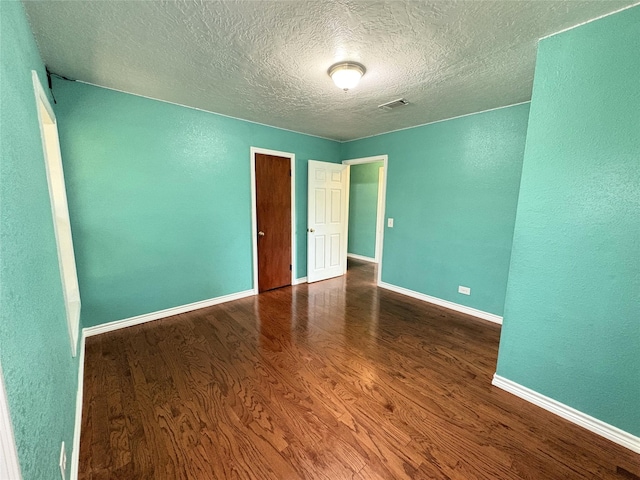 1205 Lamar, Mount Pleasant, TX 75455 - spare room featuring wood finished floors, a textured ceiling, baseboards, and a textured wall