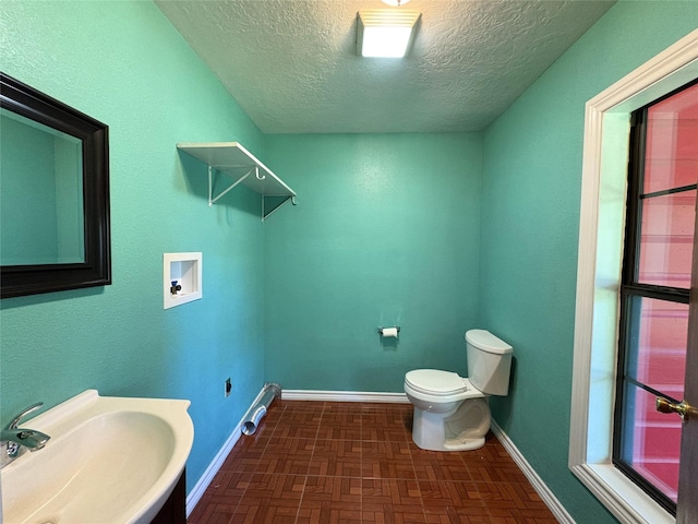 1205 Lamar, Mount Pleasant, TX 75455 - bathroom featuring a sink, toilet, a textured ceiling, and baseboards