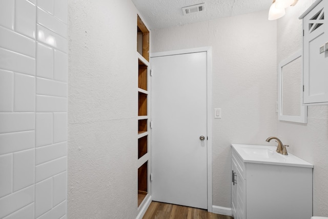 903 1st St, Bridgeport, TX 76426 - bathroom with wood finished floors, vanity, and a textured ceiling