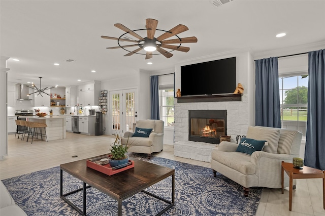 4675 County Road 2216, Caddo Mills, TX 75135 - living room with ceiling fan, a stone fireplace, light wood-style flooring, recessed lighting, and a chandelier