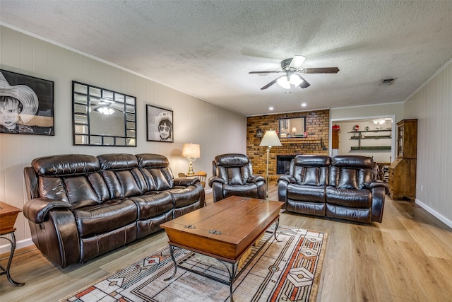 508 Fox Trl, Greenville, TX 75402 - living room with light wood-style flooring, ceiling fan, ornamental molding, a fireplace, and a textured ceiling