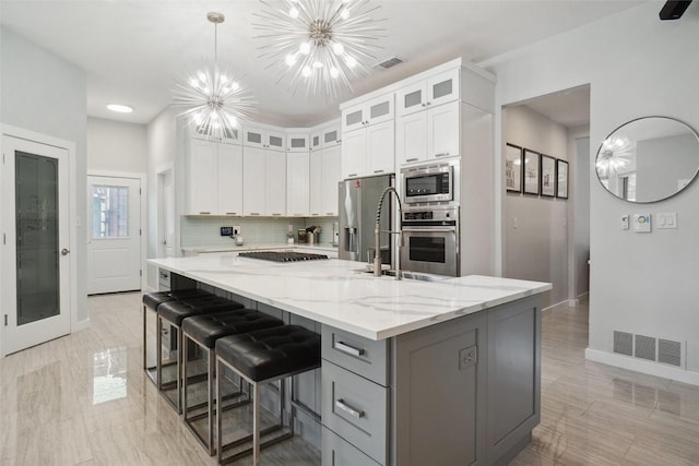 1302 Kelly Green Ct, Keller, TX 76248 - kitchen featuring stainless steel appliances, a chandelier, white cabinetry, gray cabinetry, and light stone countertops