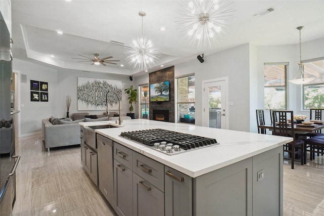1302 Kelly Green Ct, Keller, TX 76248 - kitchen with gray cabinets, stainless steel gas cooktop, open floor plan, ceiling fan, and a fireplace