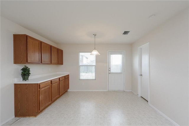 2913 Paddock Way, Denton, TX 76210 - kitchen featuring brown cabinetry, light countertops, pendant lighting, and baseboards