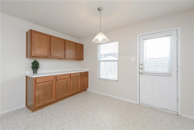 2913 Paddock Way, Denton, TX 76210 - kitchen with brown cabinets, light countertops, hanging light fixtures, and baseboards