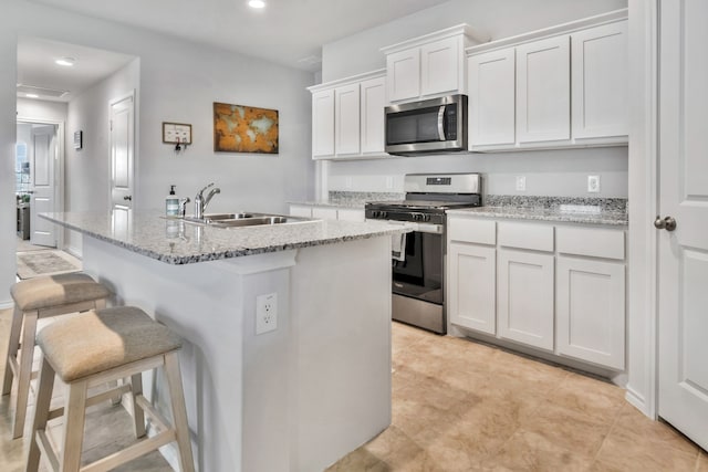16637 Friesland Ln, Justin, TX 76247 - kitchen featuring appliances with stainless steel finishes, a sink, a kitchen bar, white cabinetry, and a kitchen island with sink