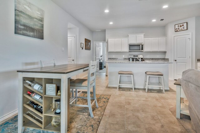 16637 Friesland Ln, Justin, TX 76247 - kitchen featuring appliances with stainless steel finishes, white cabinets, recessed lighting, a center island with sink, and a breakfast bar area