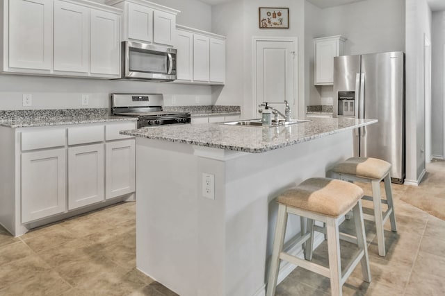 16637 Friesland Ln, Justin, TX 76247 - kitchen with appliances with stainless steel finishes, a sink, white cabinets, a breakfast bar area, and an island with sink
